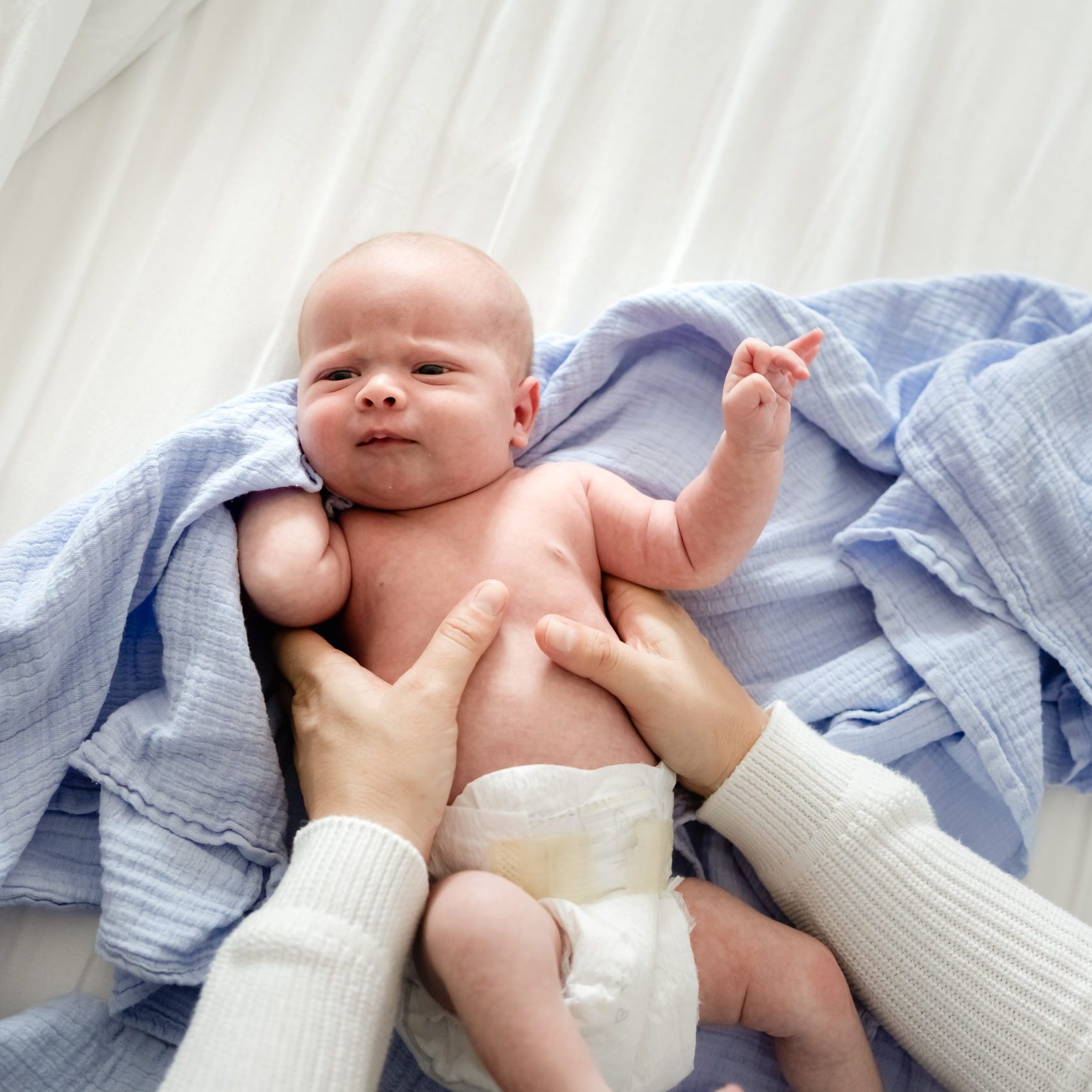 Baby boy getting ready to be swaddled during an in-home newborn photo shoot