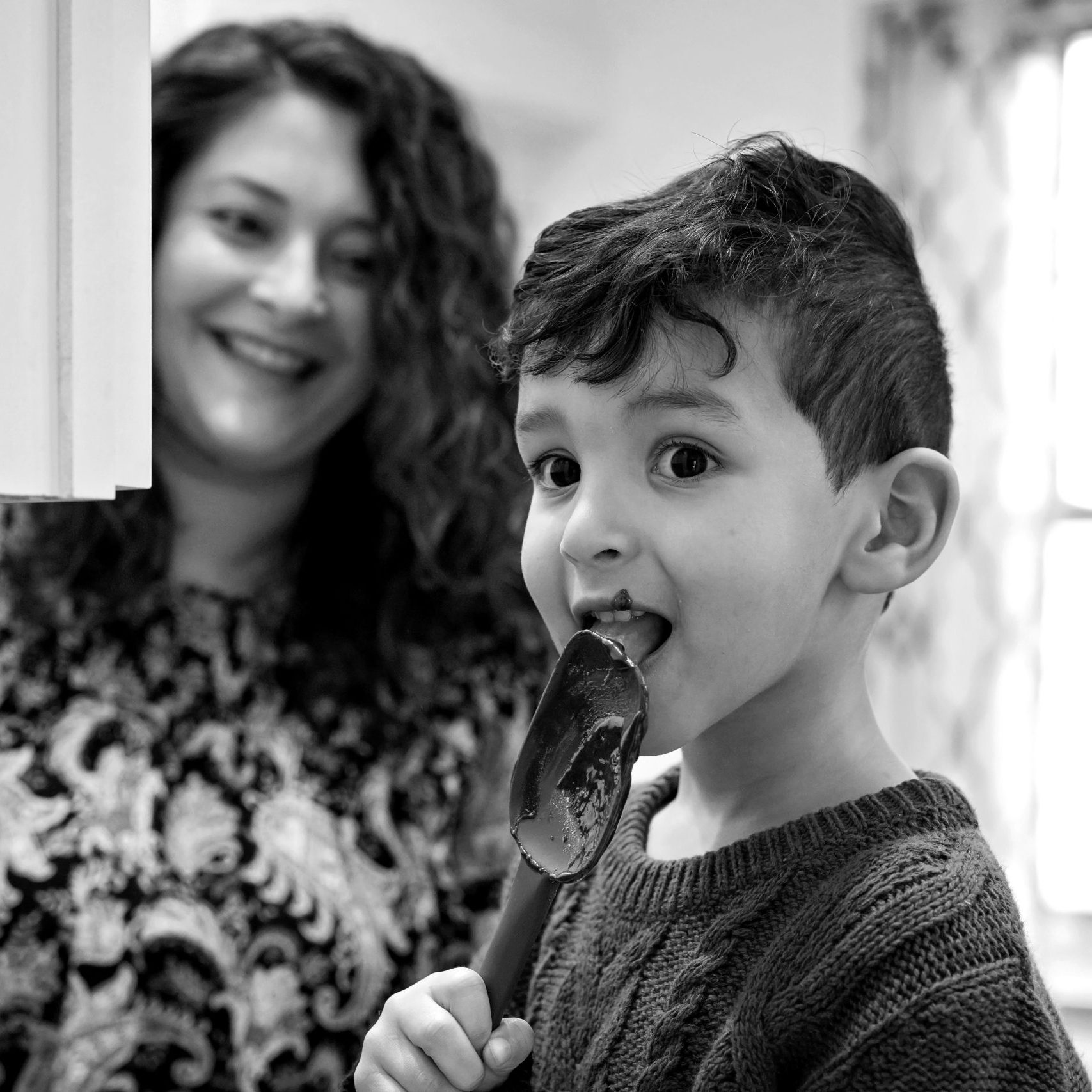 Boy licking a spatula in his kitchen during an in-home lifestyle photo shoot