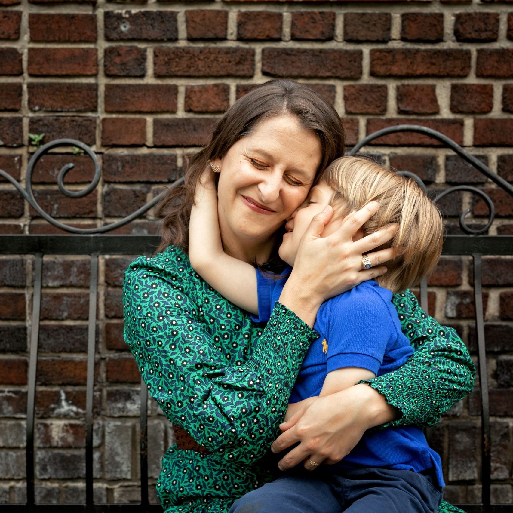 Small child hugs his mom on a bench in Mellon Park in Pittsburgh while she scrunches up her face
